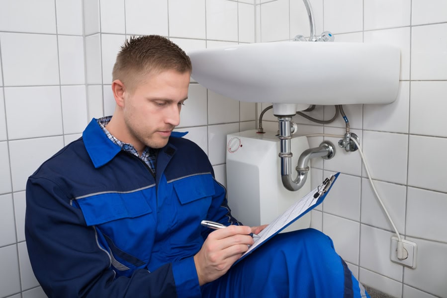 Young Plumber Writing On Clipboard.
