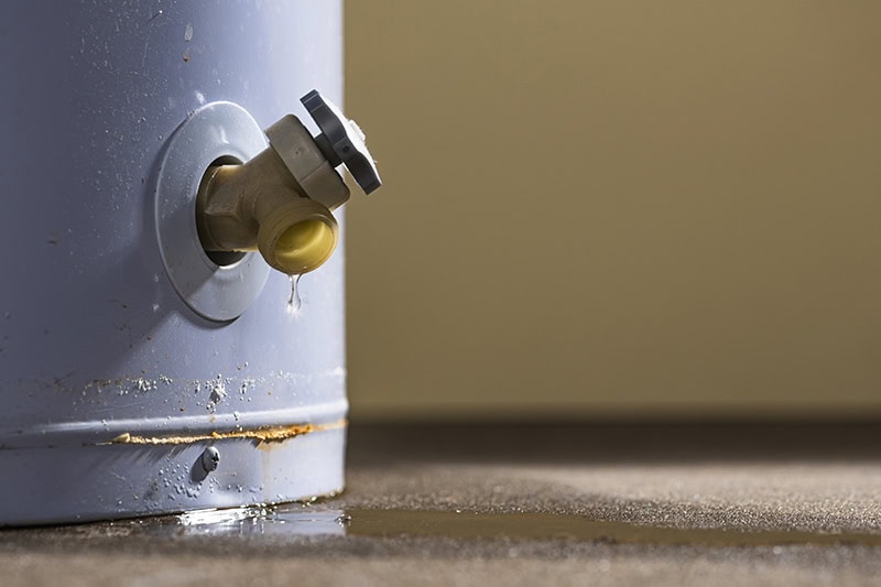 A view of water leaking from the plastic faucet on a water heater.