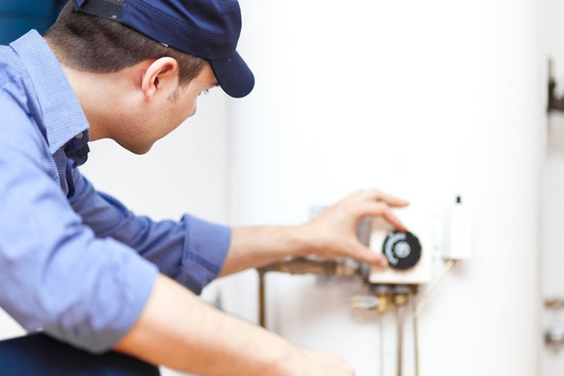 What is a Tankless Water Heater? Photo of a technician adjusting controls on a water heater.